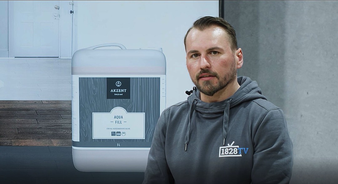 Stauf-Anwendungstechniker Florian Hees<hr>Nachgefragt bei Florian Hees<br>"Water popping"-Effekt – ein Gimmick mit Potenzial?<br><br>FussbodenTechnik: Sie haben anhand eines Logos gezeigt, wie das Wässern beim Farb-Ölen die Pigmentaufnahme des Holzes beeinflusst. Wo nutzen Sie diesen Gestaltungstechnik?<br><br>Florian Hees: Ich habe diesen Effekt bisher bei Seminaren gezeigt, indem ich im Vorfeld meine nasse Handfläche auf das Parkett gedrückt habe. Der Handabdruck wird erst nach dem Auspolieren des Öls sichtbar. Inwiefern dieser Effekt in der Praxis bisher tatsächlich gestalterisch genutzt wird, ist mir allerdings nicht bekannt. Die Idee zur Schablone (Aufkleber) war eine Idee speziell für unser 1828 TV.<br><br>FT: Wie entsteht der Effekt?<br><br>Hees: Da sich die Fasern beim Wässern des Bodens aufstellen, verbleiben in den gewässerten Bereichen mehr Farbpigmente, sodass der Farbton an diesen Stellen intensiviert wird. Bei verschiedenen Beizen ist dies notwendig. Bei farbigen Ölen ist es von Vorteil, aber nicht zwingend erforderlich.<br><br>FT: Was eignet sich als Schablone?<br><br>Hees: Der Parkettleger kann grundsätzlich mit verschiedenen Hilfsmitteln arbeiten. Er kann sowohl, wie in unserem Fall, einen Aufkleber als Schablone nutzen, aber auch Freihand mit einem Pinsel arbeiten.<br><br>FT: Was ist zu beachten, um ein gutes Ergebnis zu erzielen?<br><br>Hees: Ich sehe die primäre Problematik im Erstellen scharfer Konturen. Da Wasser unter die Schablone laufen kann bzw. das Holz Feuchtigkeit unter die Schablone zieht, können Verläufe entstehen. Deshalb habe ich die Holzplatte nicht einmal satt gewässert, wie es sonst üblich ist, sondern mit sehr wenig Wasser in mehreren Aufträgen gearbeitet. Das Resultat kann sich sehen lassen. Wässern beeinflusst die Farbintensität